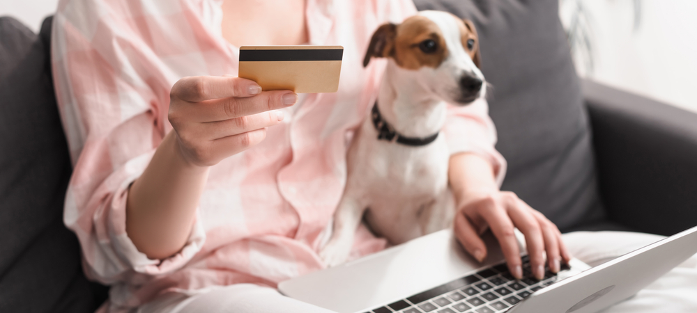 Pet owner holding credit card near dog while paying for veterinary services at Boca Midtowne Animal Hospital